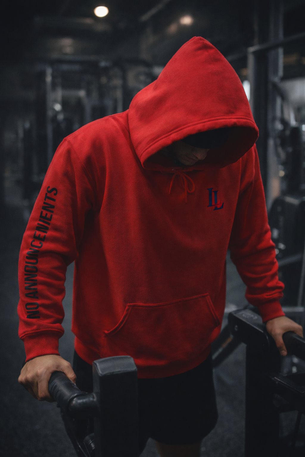 Person wearing a red hoodie with text, standing in a gym setting.